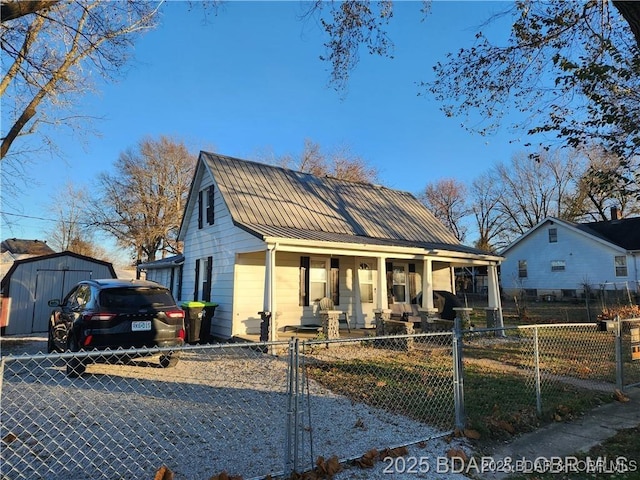 206 Oak St S, Versailles, MO 65084 - bungalow featuring a porch, a standing seam roof, a fenced front yard, a metal roof, and a storage unit