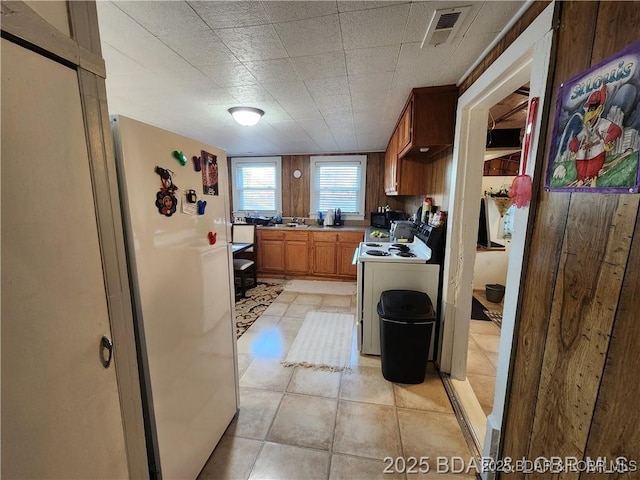 206 Oak St S, Versailles, MO 65084 - kitchen featuring white appliances, light countertops, brown cabinetry, and light tile patterned floors