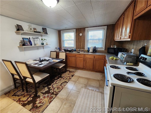 206 Oak St S, Versailles, MO 65084 - kitchen with white electric range oven, brown cabinetry, dark countertops, light tile patterned floors, and open shelves