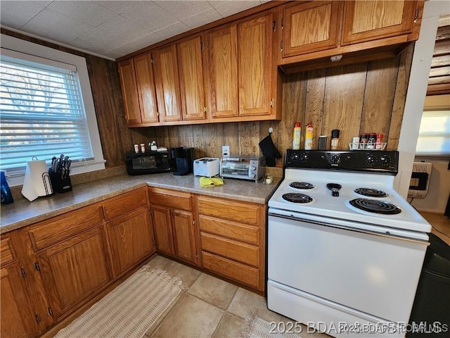 206 Oak St S, Versailles, MO 65084 - kitchen with white range with electric stovetop, brown cabinets, light tile patterned floors, and light countertops