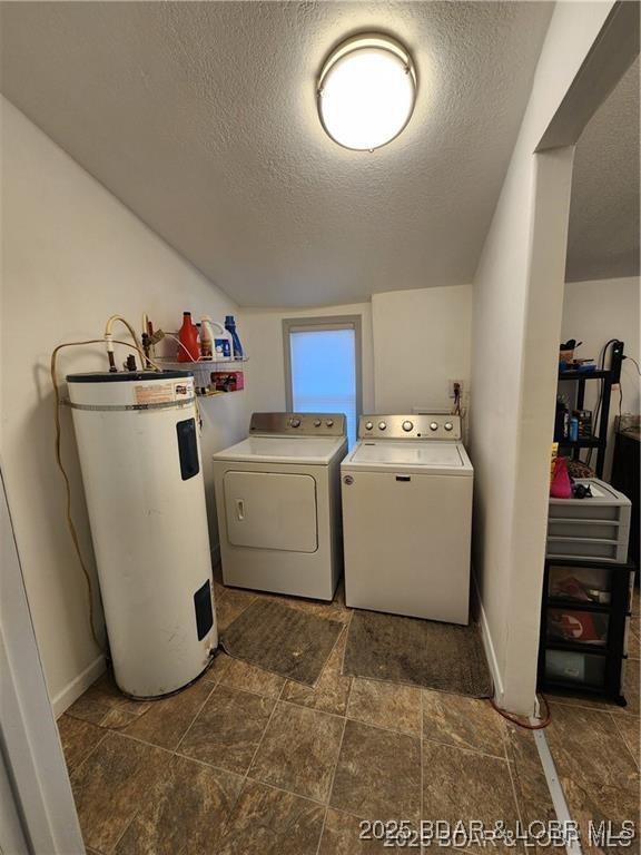 206 Oak St S, Versailles, MO 65084 - laundry room with electric water heater, washer and clothes dryer, a textured ceiling, and dark stone finish floors