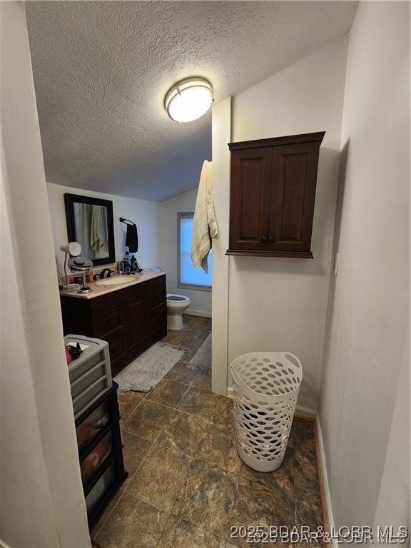 206 Oak St S, Versailles, MO 65084 - bathroom featuring a textured ceiling, stone finish floors, and vanity