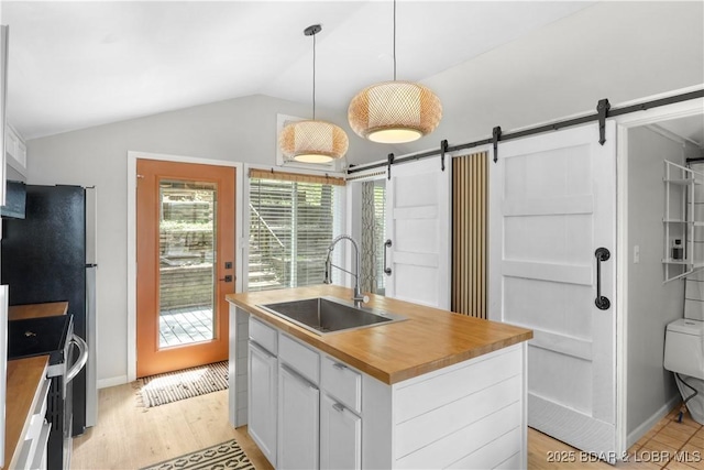 26794 Boone Rd, Barnett, MO 65011 - kitchen featuring butcher block counters, stainless steel range, a barn door, an island with sink, and vaulted ceiling