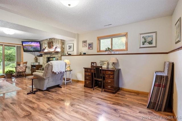 28 Wood River Rd, Lake Ozark, MO 65049 - living area with wood finished floors, a textured ceiling, and a stone fireplace