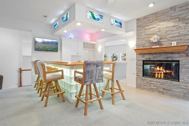 26 Port Bagnell Rd, Eldon, MO 65026 - dining room featuring bar with sink, light colored carpet, a stone fireplace, and a towering ceiling