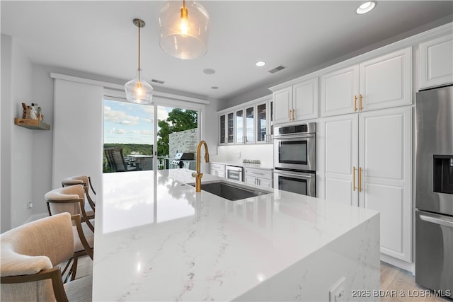 584 Black Hawk Dr, Lake Ozark, MO 65049 - kitchen with stainless steel appliances, light stone countertops, white cabinetry, recessed lighting, and hanging light fixtures