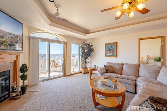 49 Aqua Fin Dr Unit 3B, Lake Ozark, MO 65049 - carpeted living room featuring a tray ceiling, a ceiling fan, and a fireplace with flush hearth
