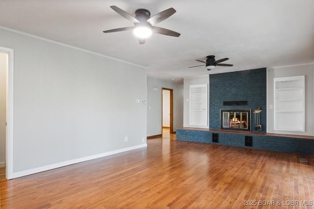 43 Bob White Ln, Lake Ozark, MO 65049 - unfurnished living room with ceiling fan, built in shelves, wood finished floors, a brick fireplace, and ornamental molding