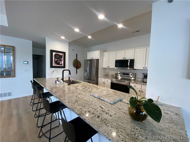 42 Palisades Lakeview Dr Unit 4B, Lake Ozark, MO 65049 - kitchen with appliances with stainless steel finishes, a kitchen breakfast bar, light stone counters, white cabinets, and wood finished floors