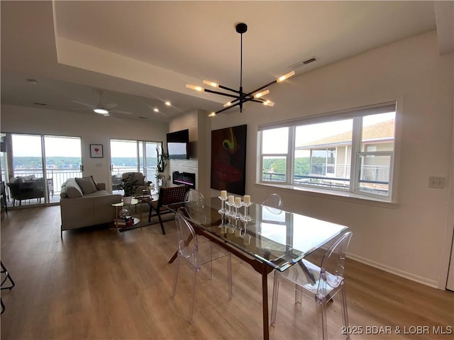 42 Palisades Lakeview Dr Unit 4B, Lake Ozark, MO 65049 - dining area featuring a chandelier, wood finished floors, a fireplace, and a ceiling fan