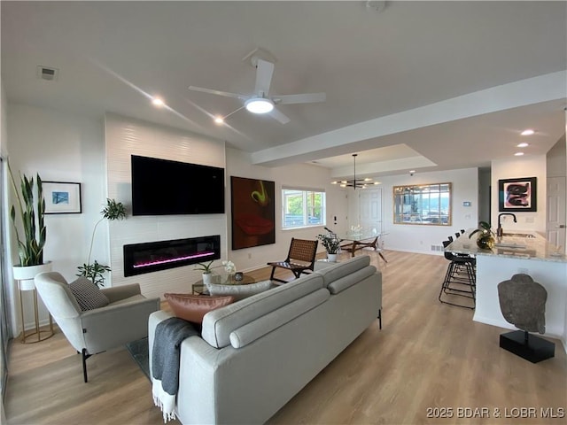 42 Palisades Lakeview Dr Unit 4B, Lake Ozark, MO 65049 - living area featuring a glass covered fireplace, light wood finished floors, a chandelier, and ceiling fan