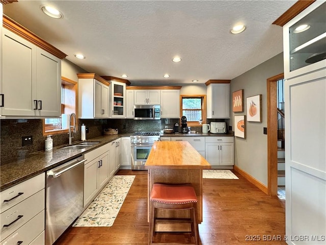 158 Oak Manor Cir, Sunrise Beach, MO 65079 - kitchen with appliances with stainless steel finishes, wooden counters, dark wood-style floors, decorative backsplash, and glass insert cabinets