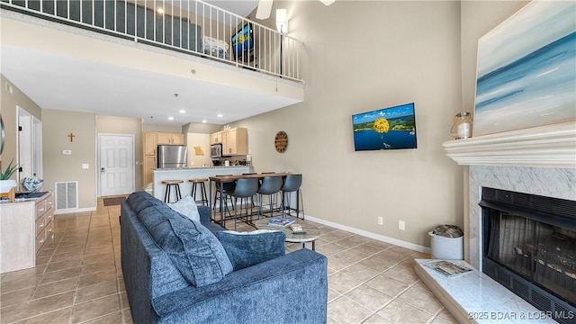 133 Cedar Glen Ct Unit 4B, Camdenton, MO 65020 - living area with light tile patterned flooring, ceiling fan, a fireplace, and a high ceiling