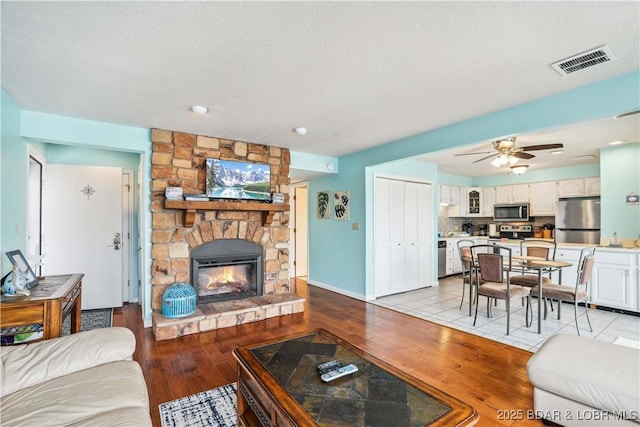 1113 Passover Rd Unit M-3, Osage Beach, MO 65065 - living room featuring light wood finished floors, a fireplace, a ceiling fan, recessed lighting, and a textured ceiling
