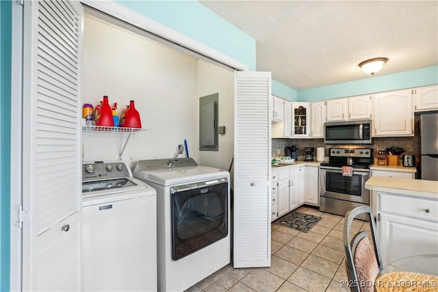 1113 Passover Rd Unit M-3, Osage Beach, MO 65065 - laundry area featuring independent washer and dryer, light tile patterned floors, electric panel, and a textured ceiling