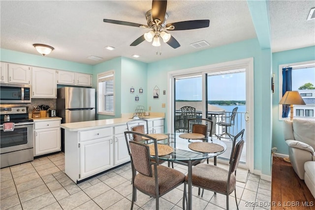 1113 Passover Rd Unit M-3, Osage Beach, MO 65065 - kitchen with appliances with stainless steel finishes, white cabinets, light countertops, a ceiling fan, and a textured ceiling
