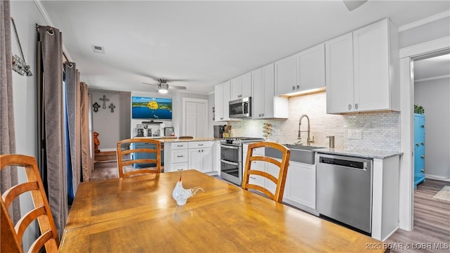 168 Moeller Way, Camdenton, MO 65020 - kitchen with appliances with stainless steel finishes, ceiling fan, backsplash, wood finished floors, and white cabinetry