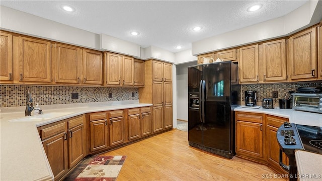 146 Palmer Dr, Lake Ozark, MO 65049 - kitchen featuring black refrigerator with ice dispenser, stove, light countertops, backsplash, and recessed lighting
