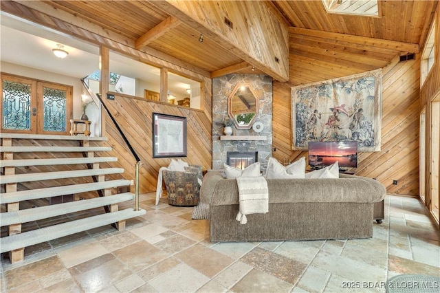 1759 Chimney Pt, Sunrise Beach, MO 65079 - living area featuring stone tile floors, wood ceiling, wood walls, stairs, and a fireplace