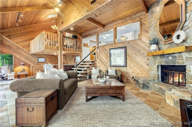 1759 Chimney Pt, Sunrise Beach, MO 65079 - living room with a wooden ceiling with exposed beams, wood walls, stairs, a fireplace, and a chandelier
