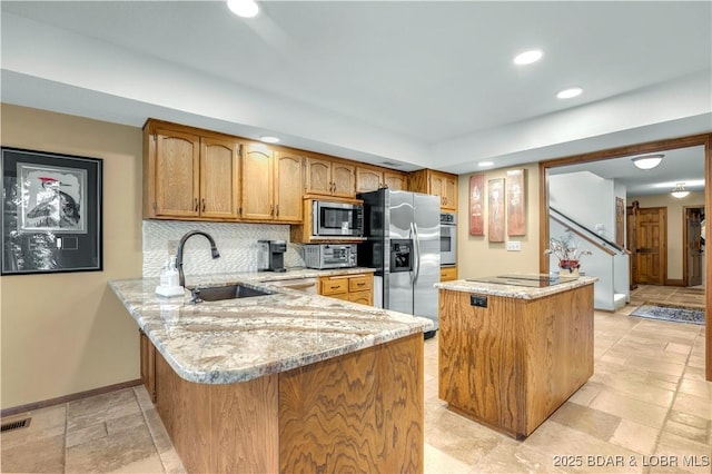 1759 Chimney Pt, Sunrise Beach, MO 65079 - kitchen featuring appliances with stainless steel finishes, a kitchen island, light stone counters, recessed lighting, and tasteful backsplash