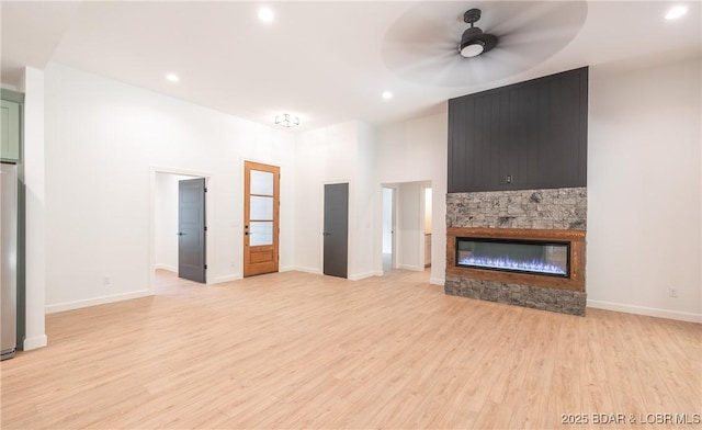 370 Via Appia Dr, Sunrise Beach, MO 65079 - unfurnished living room with light wood finished floors, a stone fireplace, a ceiling fan, and recessed lighting
