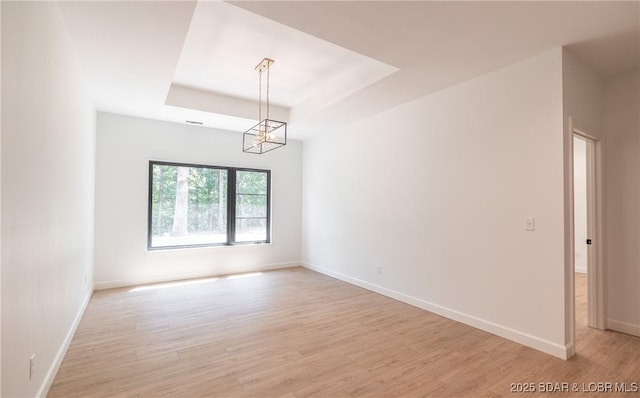 370 Via Appia Dr, Sunrise Beach, MO 65079 - empty room featuring a chandelier, light wood finished floors, and a raised ceiling