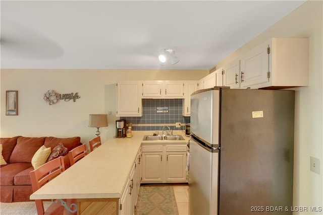 6620 Weston Point Dr Unit F4, Osage Beach, MO 65065 - kitchen featuring freestanding refrigerator, a peninsula, light countertops, tasteful backsplash, and white cabinets