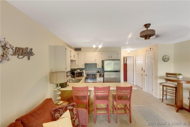 6620 Weston Point Dr Unit F4, Osage Beach, MO 65065 - kitchen with appliances with stainless steel finishes, a peninsula, decorative backsplash, light carpet, and light countertops