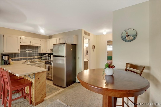 6620 Weston Point Dr Unit F4, Osage Beach, MO 65065 - kitchen featuring appliances with stainless steel finishes, white cabinets, tasteful backsplash, and light countertops