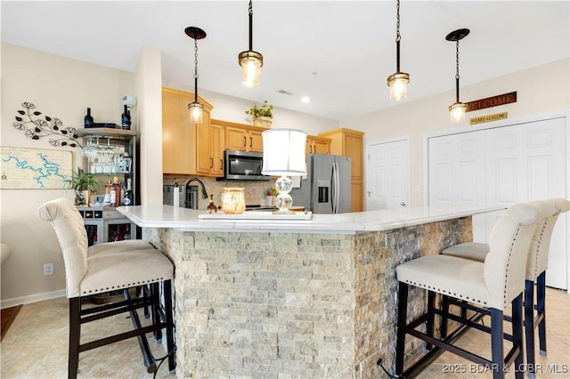 18132 Millstone Cove Rd Unit 334, Gravois Mills, MO 65037 - kitchen featuring appliances with stainless steel finishes, backsplash, a breakfast bar, a peninsula, and light brown cabinets