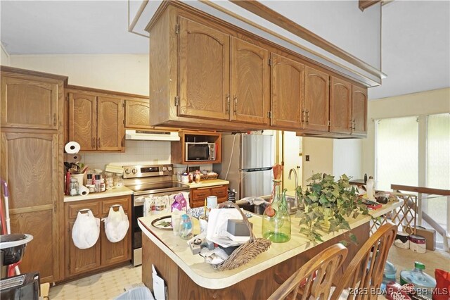 333 Crane Cove Rd, Sunrise Beach, MO 65079 - kitchen with appliances with stainless steel finishes, under cabinet range hood, light countertops, decorative backsplash, and brown cabinets