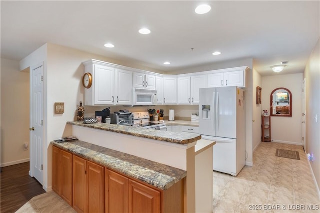 686 Clearwater Dr Unit 2C, Camdenton, MO 65020 - kitchen featuring white appliances, a peninsula, white cabinets, recessed lighting, and stone countertops