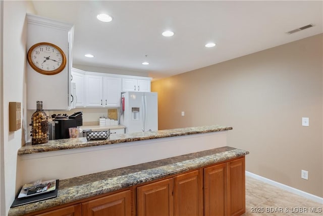 686 Clearwater Dr Unit 2C, Camdenton, MO 65020 - kitchen with white fridge with ice dispenser, dark stone countertops, white cabinets, recessed lighting, and a peninsula
