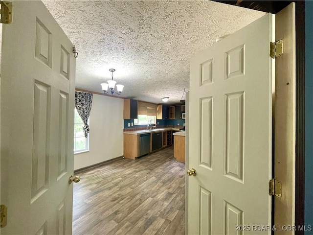 4712 Camden Line Rd, Lebanon, MO 65536 - kitchen featuring dishwasher, a chandelier, a textured ceiling, brown cabinetry, and wood finished floors