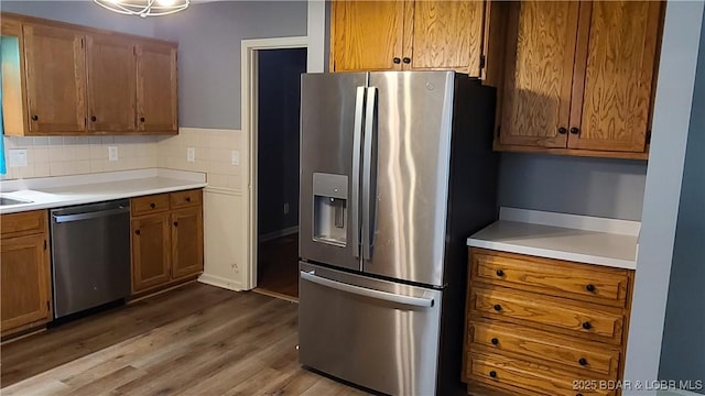508 Hunter St N, Versailles, MO 65084 - kitchen featuring stainless steel appliances, wood finished floors, light countertops, and brown cabinetry