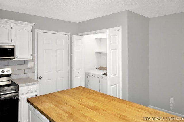 712 Passover Rd, Osage Beach, MO 65065 - kitchen with appliances with stainless steel finishes, washing machine and clothes dryer, white cabinetry, wooden counters, and decorative backsplash