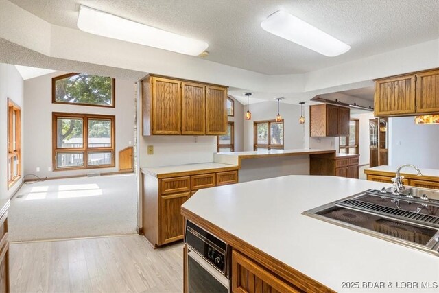 948 Cable Point Dr, Climax Springs, MO 65324 - kitchen with light wood-style flooring, light countertops, brown cabinets, a textured ceiling, and hanging light fixtures