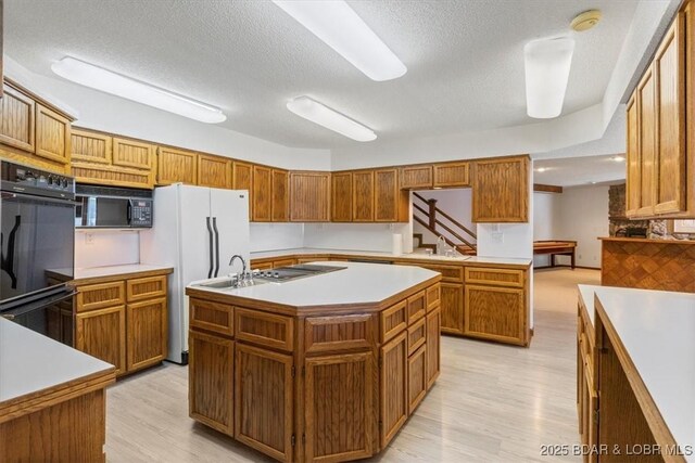 948 Cable Point Dr, Climax Springs, MO 65324 - kitchen featuring black appliances, a center island with sink, light countertops, light wood-style flooring, and brown cabinets
