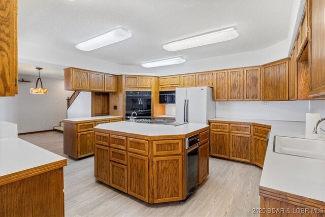 948 Cable Point Dr, Climax Springs, MO 65324 - kitchen featuring freestanding refrigerator, an island with sink, brown cabinets, cooktop, and light wood-type flooring