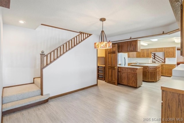 948 Cable Point Dr, Climax Springs, MO 65324 - kitchen featuring freestanding refrigerator, light wood-style floors, brown cabinets, light countertops, and pendant lighting