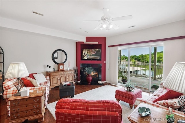 562 Hyd A Way Rd Unit 3F, Camdenton, MO 65020 - living area with a ceiling fan, dark wood-style floors, a warm lit fireplace, and a water view