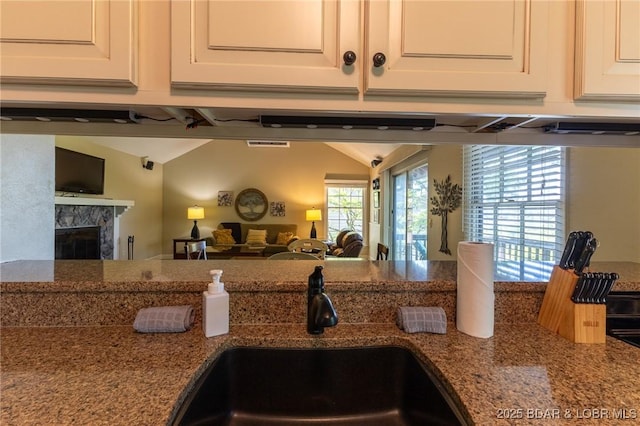 415 Staniel Cay Dr, Osage Beach, MO 65065 - kitchen with white cabinets, stone countertops, vaulted ceiling, a fireplace, and open floor plan