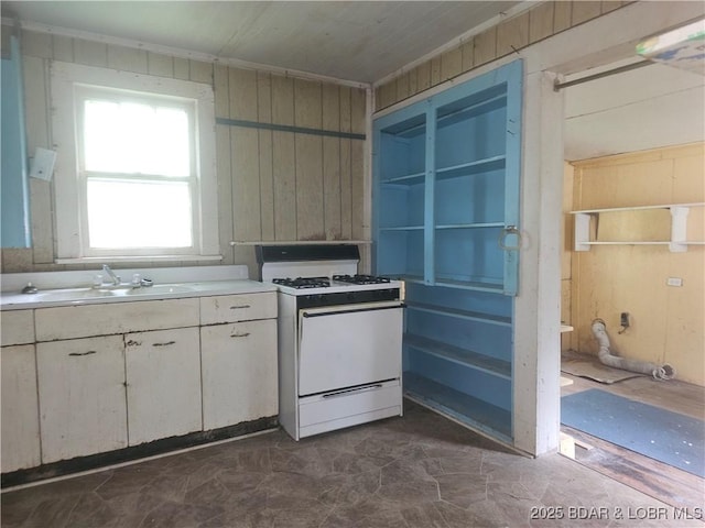 412 Maple St, Eldon, MO 65026 - kitchen with white gas range oven, light countertops, white cabinets, and wood walls