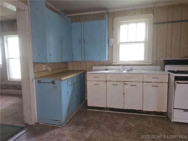 412 Maple St, Eldon, MO 65026 - kitchen with white range with gas cooktop, light countertops, blue cabinetry, and wood walls