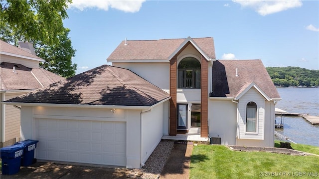 2268 Breezy Acres Rd, Osage Beach, MO 65065 - view of front of house with stucco siding, a water view, a garage, and a front lawn
