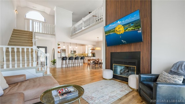 2268 Breezy Acres Rd, Osage Beach, MO 65065 - living room featuring a towering ceiling, wood finished floors, stairway, and a glass covered fireplace
