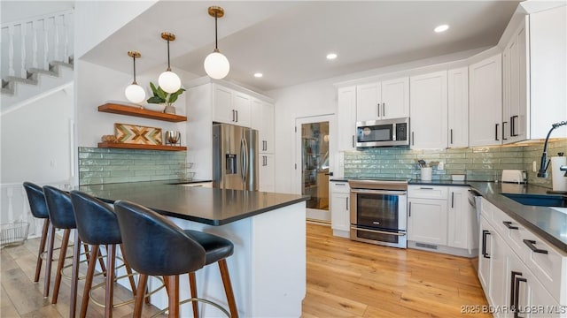 2268 Breezy Acres Rd, Osage Beach, MO 65065 - kitchen featuring stainless steel appliances, dark countertops, open shelves, a peninsula, and white cabinetry