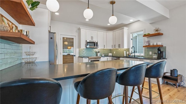 2268 Breezy Acres Rd, Osage Beach, MO 65065 - kitchen with open shelves, appliances with stainless steel finishes, dark countertops, a peninsula, and white cabinetry