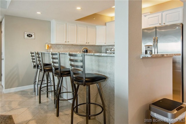 68 Lighthouse Rd Unit 906, Lake Ozark, MO 65049 - kitchen featuring white cabinetry, a kitchen bar, tasteful backsplash, light tile patterned floors, and recessed lighting